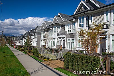 Suburban residential street townhomes. On bright sunny spring day against bright blue sky. Stock Photo