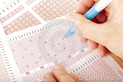 Succes concept - Person`s Hand Marking Number On Lottery Ticket With Pen Stock Photo