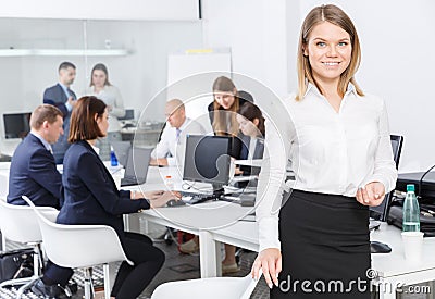 Succesful smiling young businesswoman near workplace in office Stock Photo