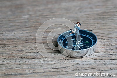 Success family guidance for bright future direction, happy miniature couple husband holding wife standing on compass on wood back Stock Photo