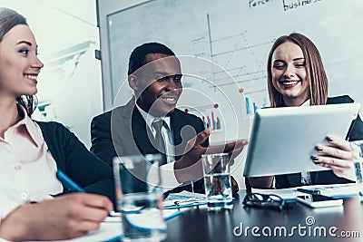 Success smiling woman shows something on computer tablet to black businessman at business meeting. Stock Photo