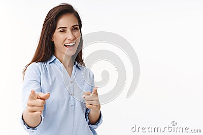 Successful ambitious brunette woman 30s congratulate coworker good job, pointing camera finger pistols, wink joyfully Stock Photo