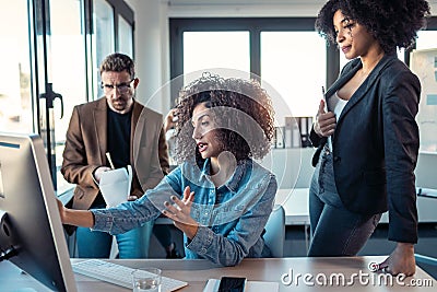 Successful business multiage team standing around computer for presentation of work in the coworking space Stock Photo