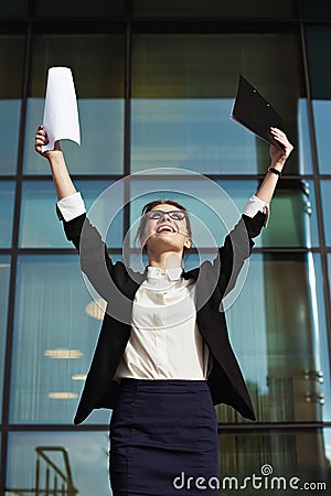 Successful business woman with arms up and documents. Stock Photo