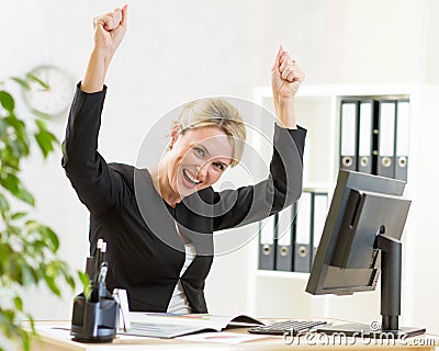 Successful business woman with arms up in office Stock Photo