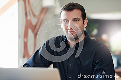 Successful businessman smiling and using a laptop in an office Stock Photo