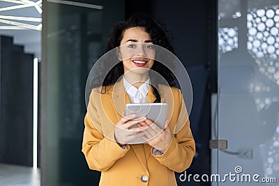 Successful businesswoman inside office building smiling and looking at camera, mature adult hispanic holding tablet Stock Photo
