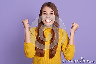 Successful caucasian female student clenches fists, accomplishes goal, exclaims finally victory, happy lady stands amused isolated Stock Photo