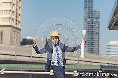 Successful engineer finishing project complete. holding fist and construction blue print in the air sign of victory. Success Stock Photo