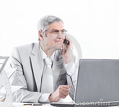 Experienced businessman with mobile phone sitting at his Desk Stock Photo