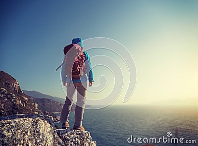 hiker stand on sunrise seaside mountain cliff edge Stock Photo