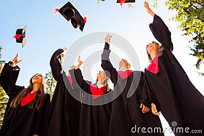 Successful five students with congratulations together throwing graduation hats in the air and celebrating Stock Photo