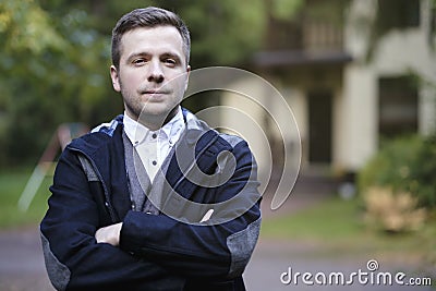 A successful and handsome young man stands next to the house bought. Stock Photo