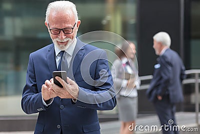 Successful happy senior businessman using smart phone, browsing internet or messaging Stock Photo