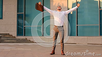 Successful lucky happy arabic business man boss entrepreneur with briefcase rise hands in air standing in city near Stock Photo