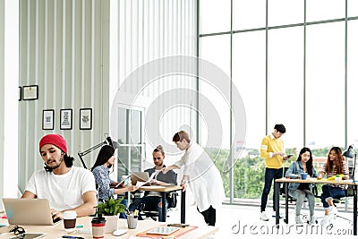 Successful multiethnic business team in routine work creative lifestyle standing, sitting and talking together at modern office Stock Photo