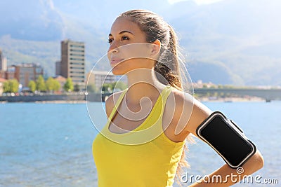 Successful positive female athlete wearing armband blank for advertising before running or exercising outdoor in summer. Woman Stock Photo