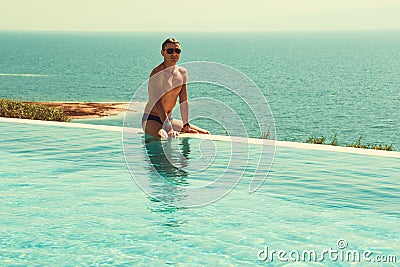 Successful rich man relaxing in infinity pool and enjoy vacation. Spa resort. Luxury lifestyle. Body care concept. Dead Sea view. Stock Photo