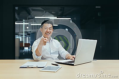 Successful seller asian businessman happy and smiling looking at camera pointing finger forward man in office working Stock Photo