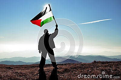 Successful silhouette man winner waving Palestine flag on top of the mountai Stock Photo