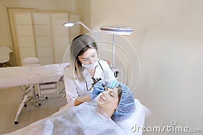 Successful woman getting permanent makeup at cabinet of professional cosmetologist. Stock Photo