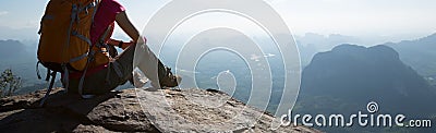 Woman traveler sitting on mountain peak cliff edge Stock Photo