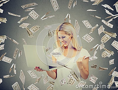 Successful woman using laptop building online business making money dollar bills falling down. Stock Photo