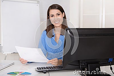 Successful young smiling business woman sitting in her office. Stock Photo