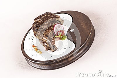 Succulent grilled large t-bone steak garnished with herbs, radish and salt, on a white plate, brown background Stock Photo