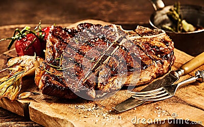 Succulent grilled t bone steak with fork and knife Stock Photo