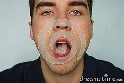 Sucking pill for sore throat in mouth. A young man sick with SARS or the flu or colds Peppermint for fresh breath, close - up of o Stock Photo