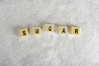 Sugar block letters in crossword over sugar pile isolated on grainy white sugar texture in sweet food abuse Stock Photo