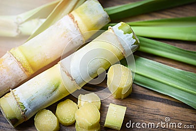 sugar cane and green leaf cut sugarcane piece on wooden table background Stock Photo