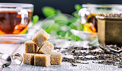 Sugar. Cane sugar. Cane sugar cubes heap close up macro shot. Tea in a glass cup, mint leaves, dried tea, sliced lime, cane brown Stock Photo