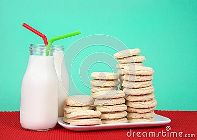 Sugar cookies stacked on plate with two bottles of milk Stock Photo