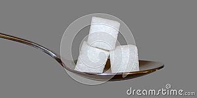 Sugar cubes on a spoon against a grey background. Stock Photo