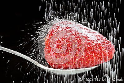 Sugar powder pour on a strawberry in a spoon on black background Stock Photo
