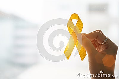 Suicide prevention and Childhood Cancer Awareness, Yellow Ribbon on wooden background for supporting people living and illness. Stock Photo