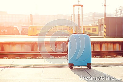 Suitcase at train station. Traveler suitcase at platform. Copy space. Blue modern luggage bag outdoors. Travelling and lifestyle c Stock Photo