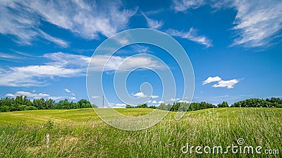 summer agricultural landscape. a hilly field under a blue cloudy sky Stock Photo