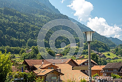 Summer alpine landscape. A small village surrounded by forest and mountains. Stock Photo