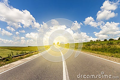 Summer asphalt road in sunrise to the sun. Beautiful yellow field with sun flare effect countryside landscape Stock Photo