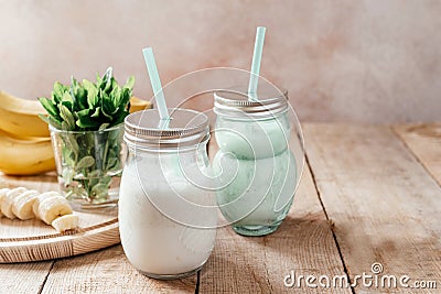 Summer banana smoothie or milkshake with mint and straw in jars on dark wooden tablen with copy space Stock Photo