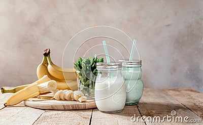 Summer banana smoothie or milkshake with mint and straw in jars on dark wooden tablen with copy space Stock Photo