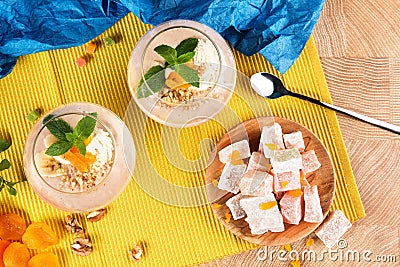 Summer banana smoothies in a huge glasses with Turkish Delight, dried apricots and walnuts on multi-colored background Stock Photo