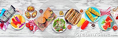 Summer BBQ food table scene with hamburgers and hot dogs over a white wood banner Stock Photo