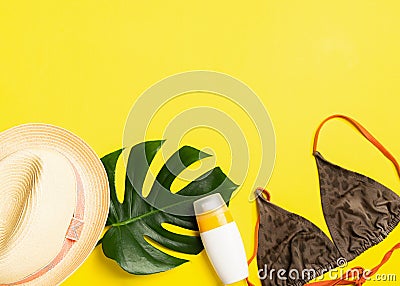 Summer beach accessories sunscreen summer hat swimsuit bright yellow background. Summer holiday concept and beach. Stock Photo