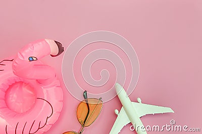 Summer beach composition. Minimal simple flat lay with plane sunglasses and Inflatable flamingo isolated on pastel pink background Stock Photo