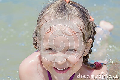 Summer beach fun of little girl kid splashing and floating in sea Stock Photo