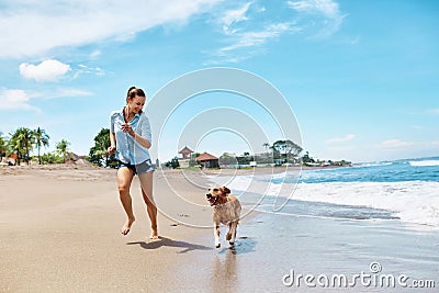 Summer Beach Fun. Woman Running With Dog. Holidays Vacations. Summer Stock Photo